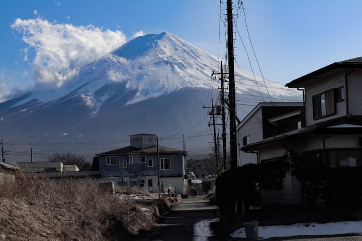 Town scene of Mount Fuji, with snow covering the top half, a cloud passing by, thumbnail
